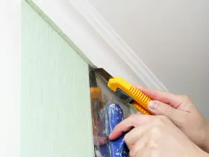 muškarac lepi tapete seče skalpelom